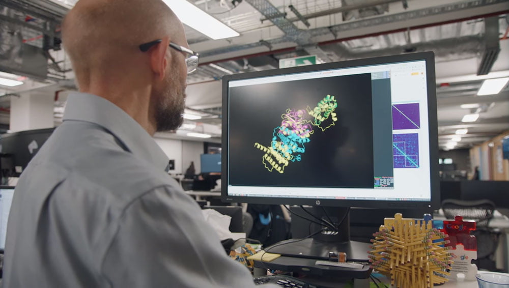 Ein Mann betrachtet auf einem Monitor eine Proteinfaltung.