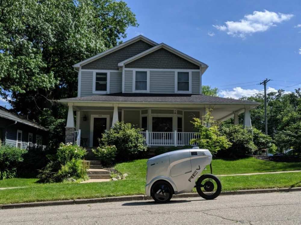 Ein autonom fahrender Lieferroboter fährt durch ein Wohngebiet.