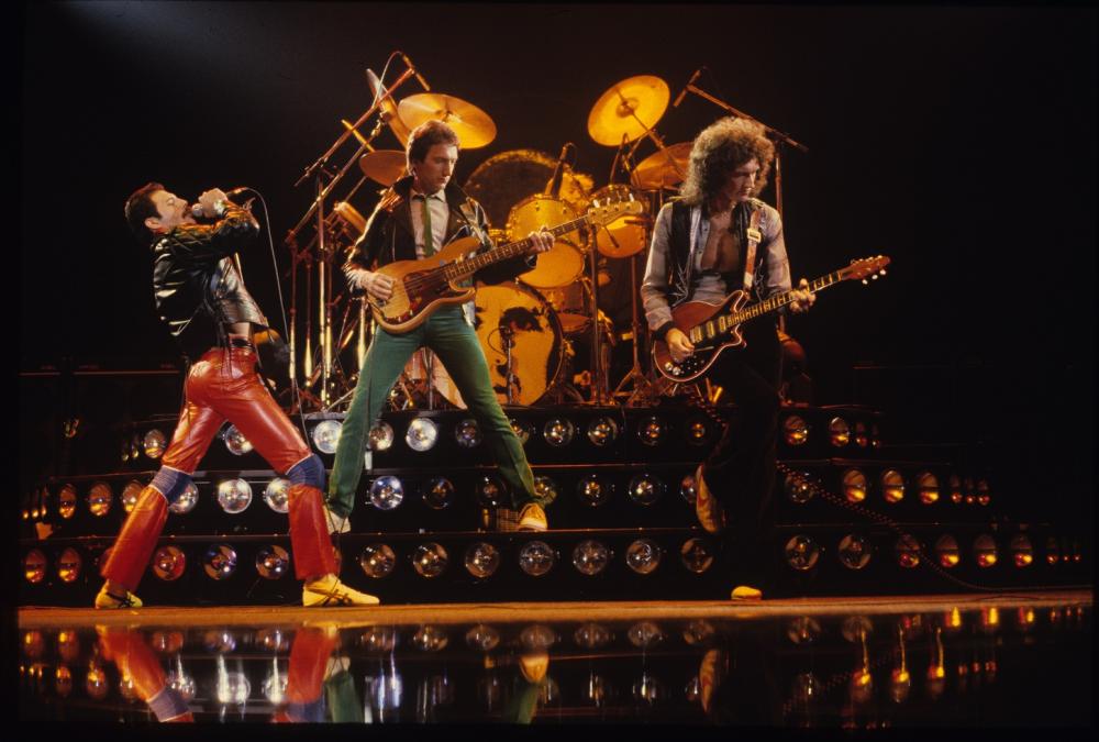 Eine Werbebild für ein Alexa Skill, das die Rockband Queen auf einer Bühne zeigt.