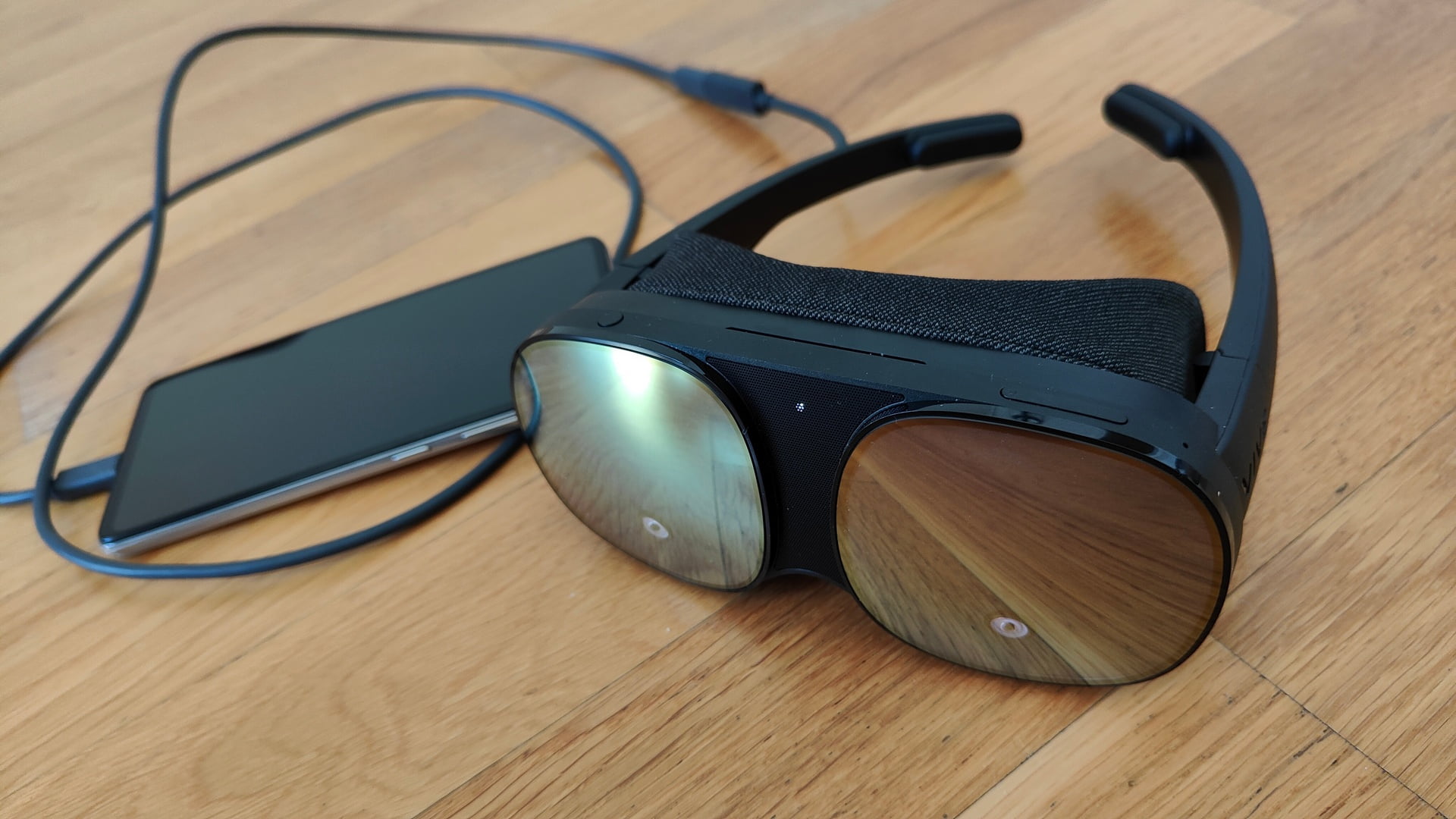 VR-Brille Vive Flow von vorne mit Smartphone, das über ein Kabel angeschlossen ist