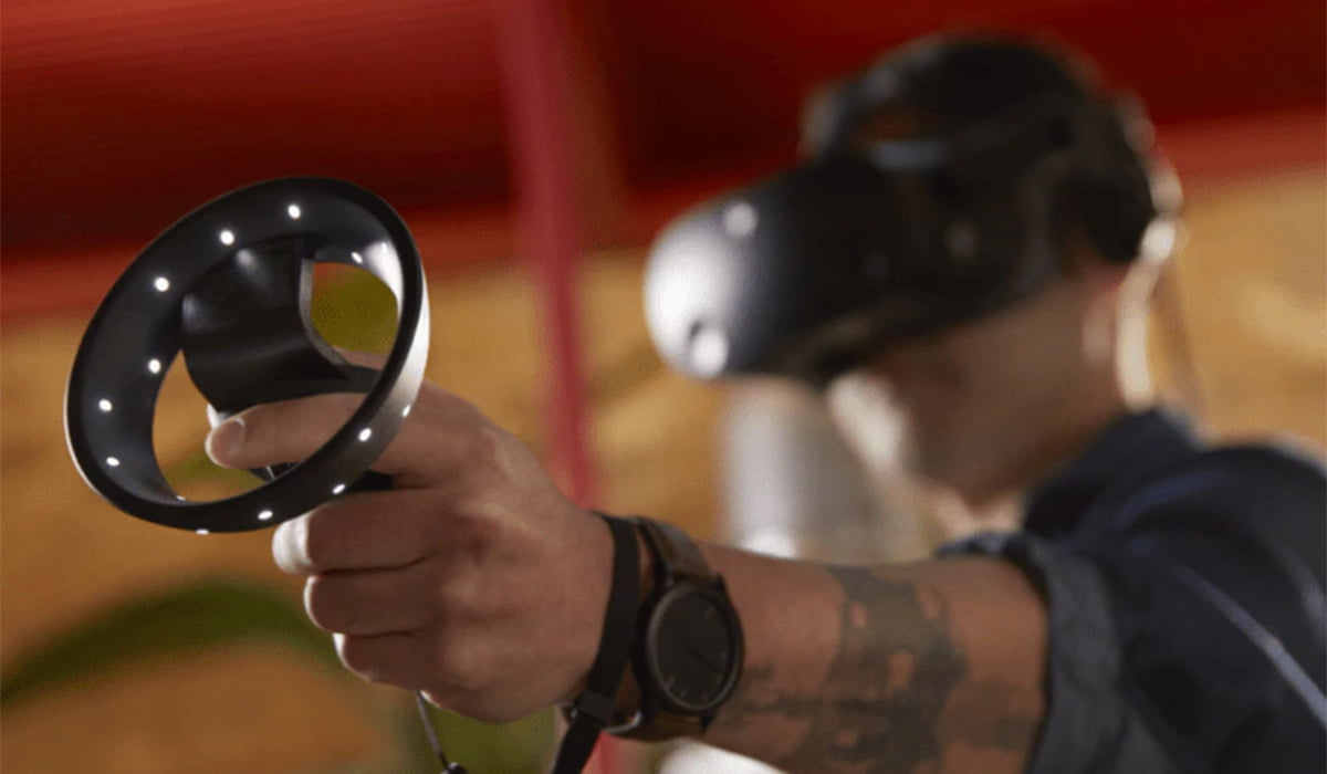 Ein Mann mit VR-Brille G2 hält einen VR-Controller in die Kamera