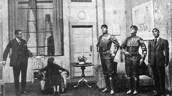 Bildunterschrift: Eine Szene aus Čapeks 1921 uraufgeführtem Stück R.U.R. – Rossum’s Universal Robots, in der drei Roboter zu sehen sind. (https://commons.wikimedia.org/wiki/File:Capek_play.jpg Public domain, via Wikimedia Commons)