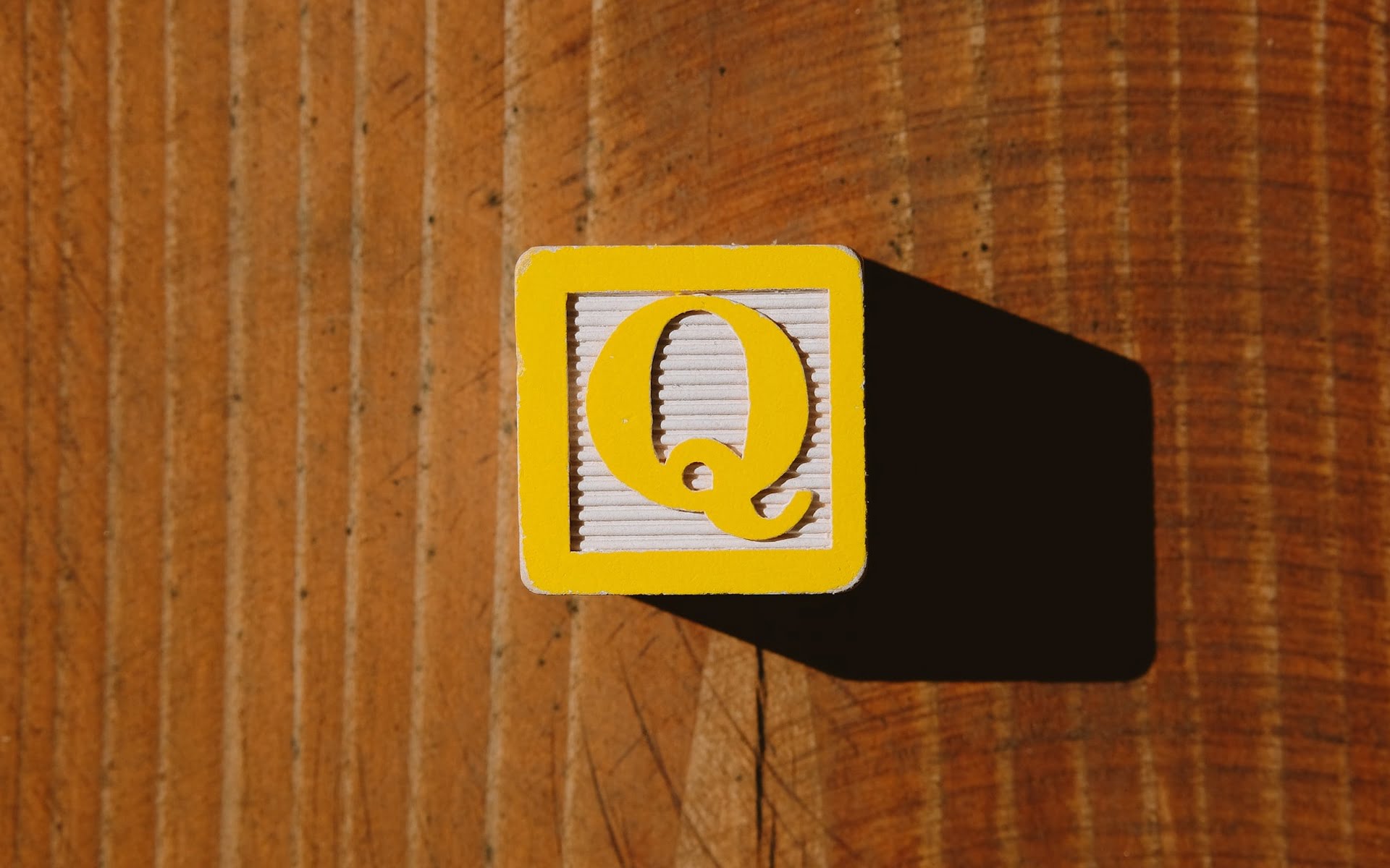 Gelber Würfel mit dem Buchstaben Q