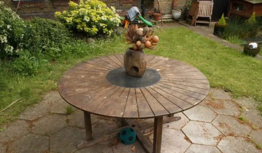 Ein Gesteck steht auf einem Gartentisch vor einer Gartenkulisee.