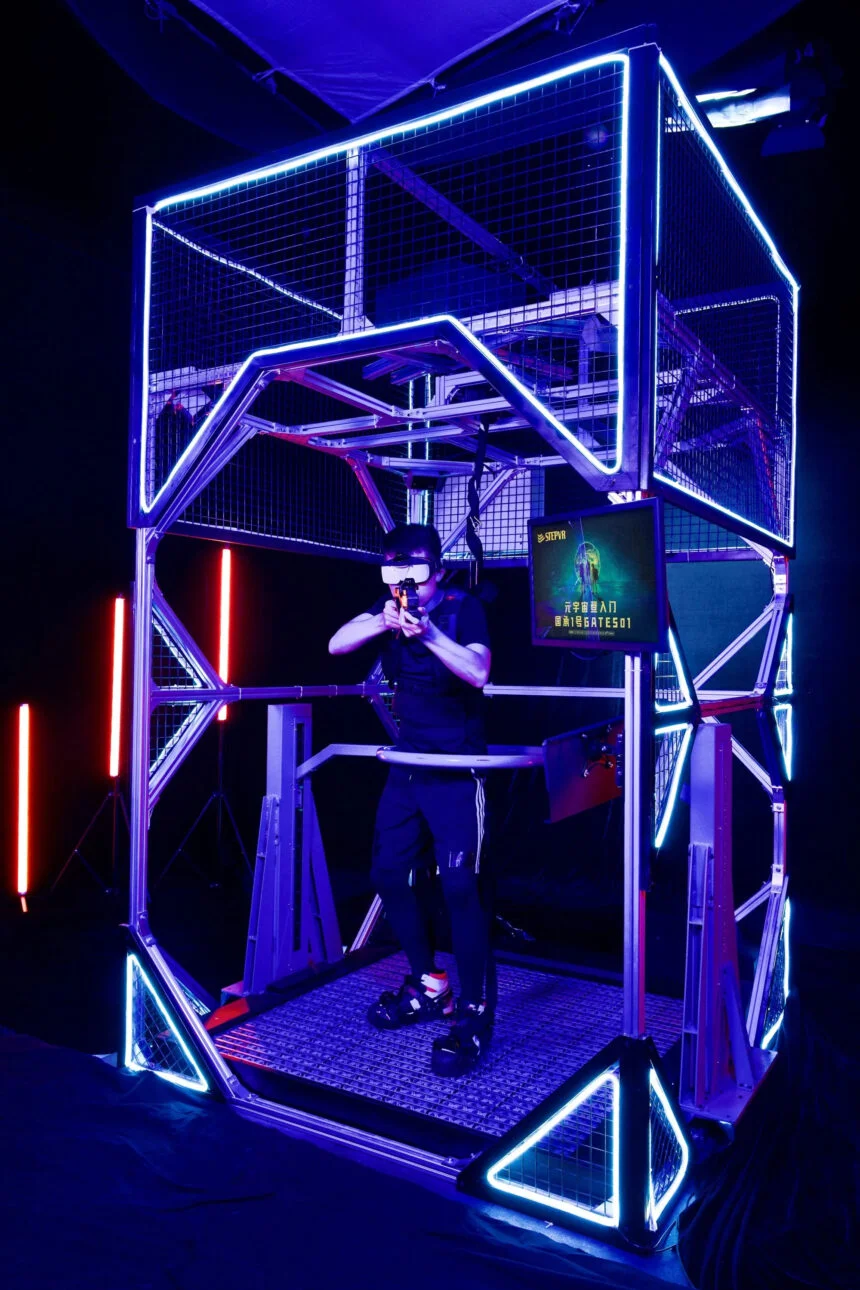 Ein Mann steht in einem Käfig mit einer VR-Brille und einer Plastikkanone.