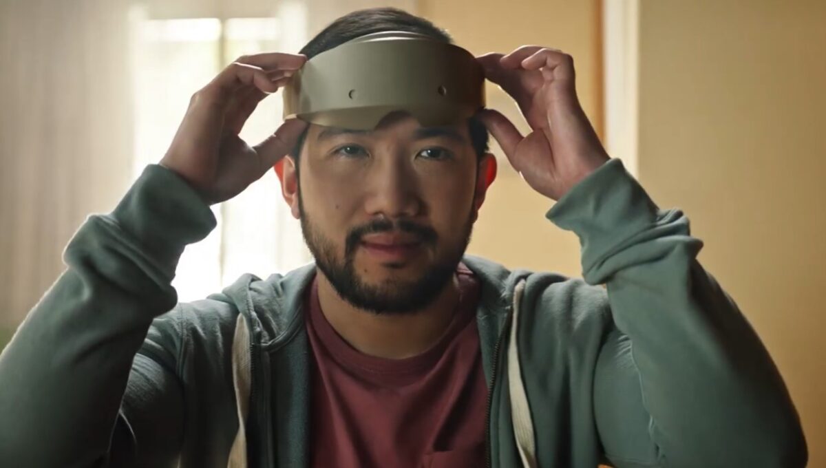 Ein Mann setzt sich eine schlanke VR-Brille auf.