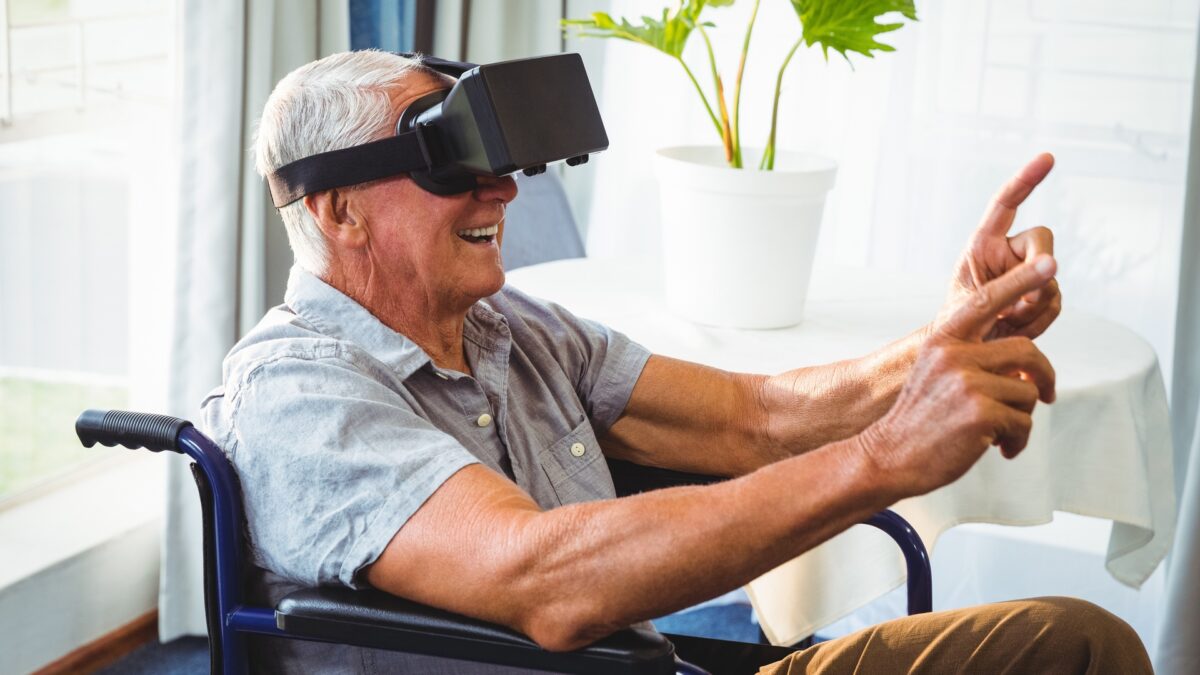 Senior im Rollstuhl mit VR-Brille lächelt aufgrund einer VR-Erfahrung