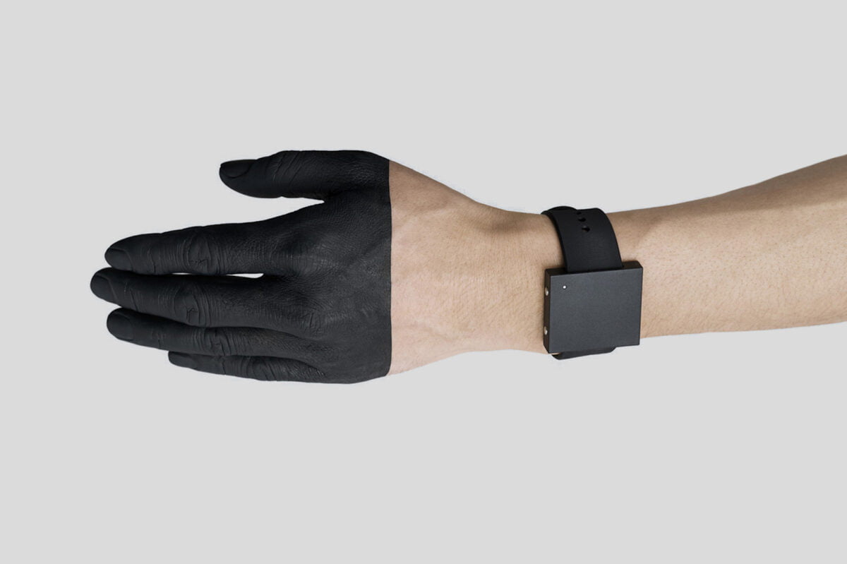 Eine ab der Mitte schwarz gefärbten Hand mit Lofelts Basslet-Wearable.