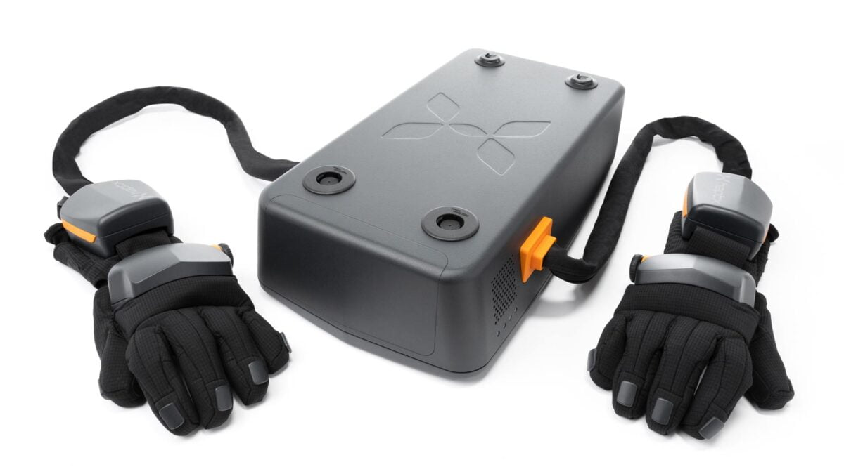 Das HaptX Airpack ist eine dunkle Box, aus der zwei Schläuche herausragen, an deren Ende die Haptik-Handschuhe befestigt sind.