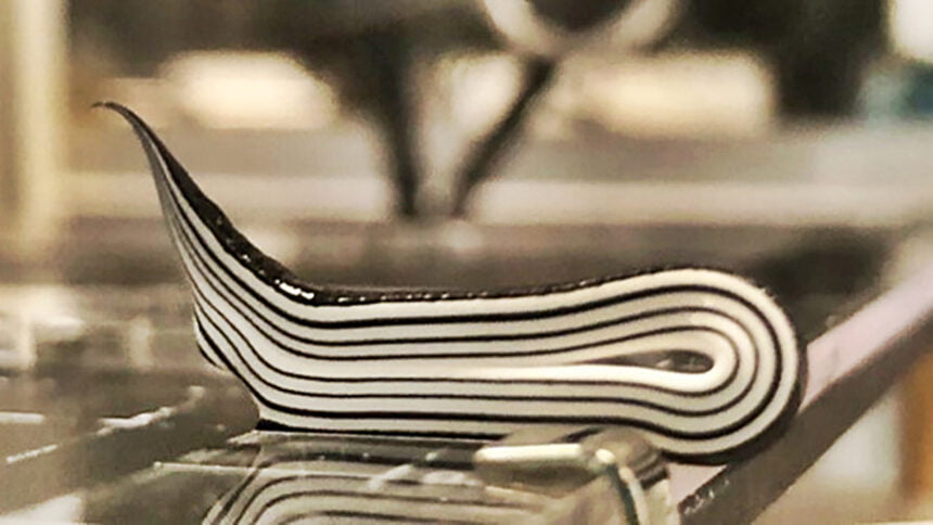 Creme-förmiges Polymer mit schwarzen und weißen Streifen liegt auf einem Metalltisch.