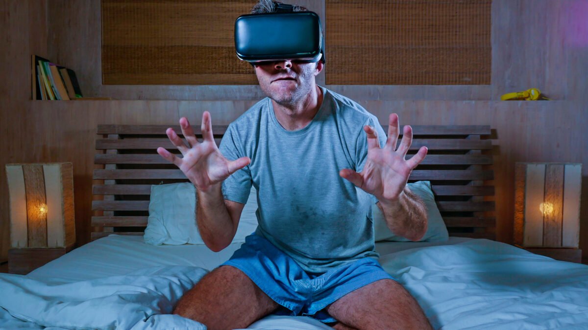 Mann auf Bett mit VR-Brille schaut offenbar VR-Porno