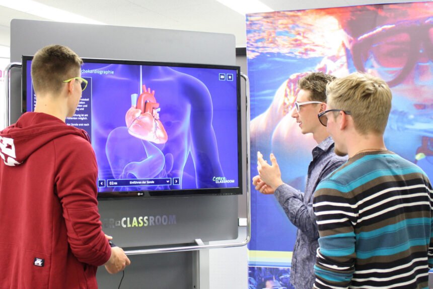 CyberClassroom 3D-TV mit der Darstellung eines menschlichen Herzens, davor drei junge Leute mit 3D-Brillen