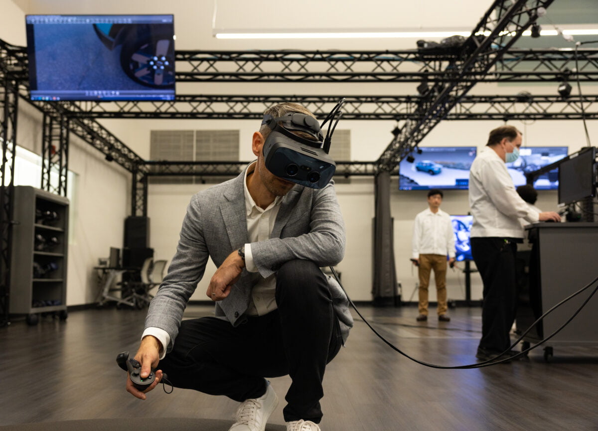 Hondas VR Design Leader Mathieu Geslin überprüft kauernd ein Fahrzeugdesign mit einer Varjo-VR-Brille.