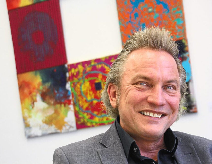 Martin Zimmermann vor einem lächelnd im Portraitfoto vor einer Kunstcollage