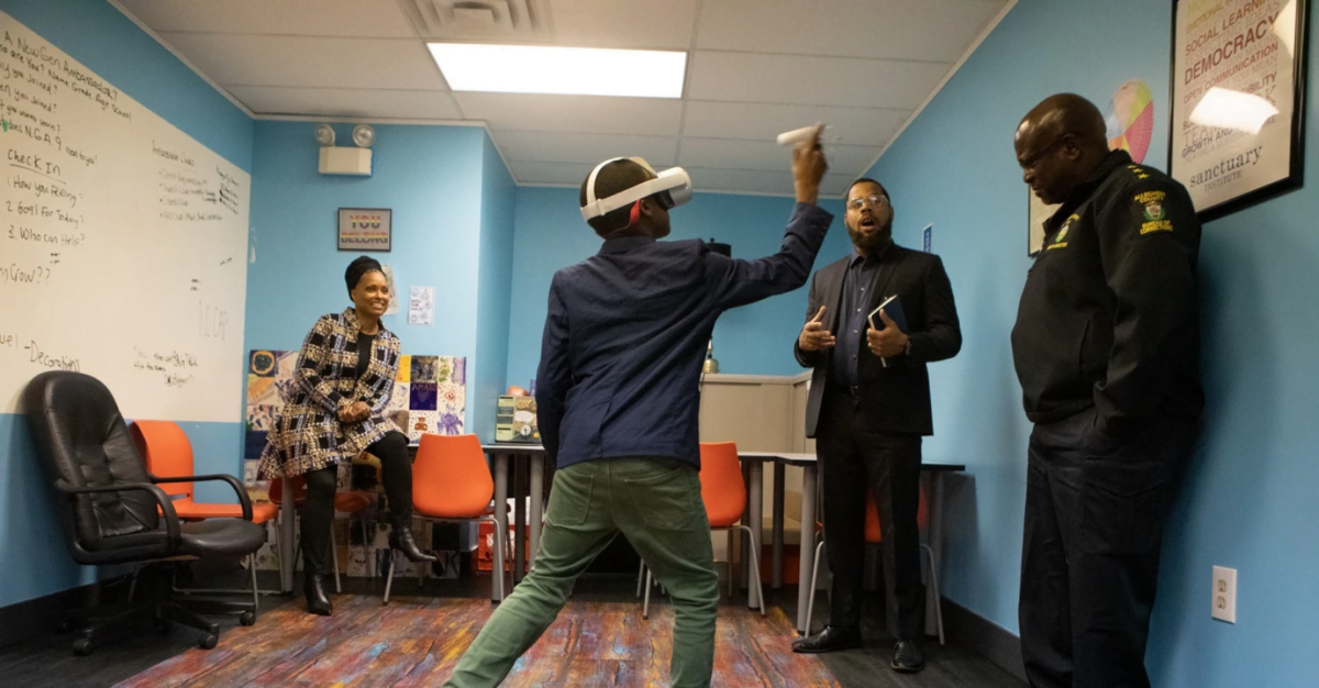 Junge mit VR-Brille probiert in einem Raum mit drei weiteren Menschen eine VR-Erfahrung aus