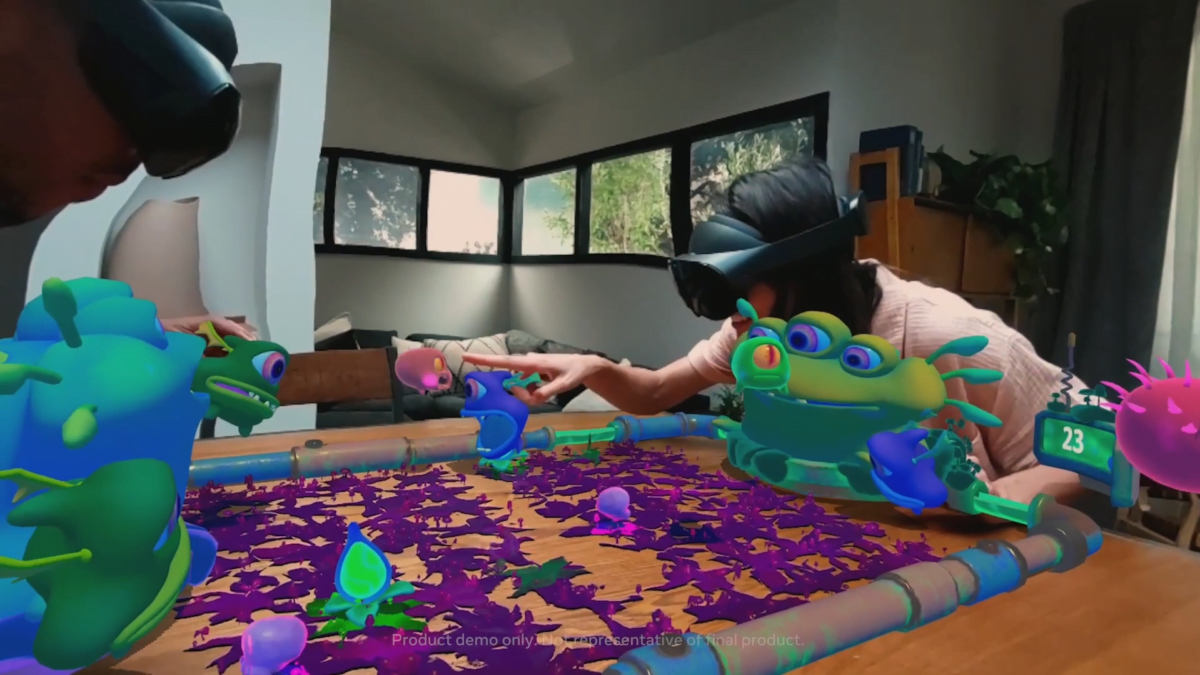 Zwei Spielende mit Quest-Pro-Brillen sehen im AR-Spiel Slimeball! virtuelle bunte Aliens auf dem realen Tisch.