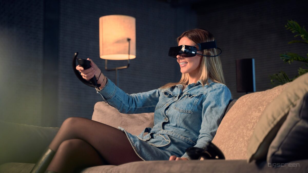 Bigscreen Beyond VR Brille, getragen von einer Frau, die auf einer Couch sitzt.