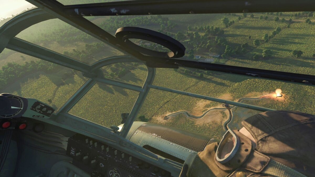 Sicht ins Cockpit eines Piloten. Unter ihm eine grüne Landschaft mit Bäumen.