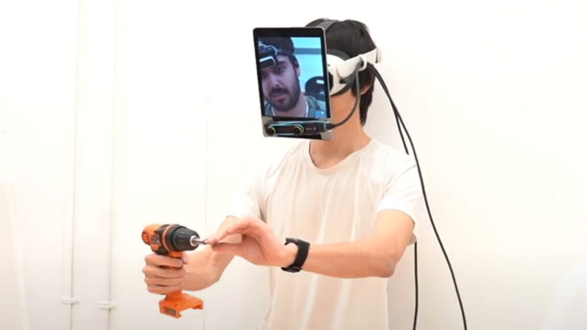 Ein Mann schraubt ein Bauteil zusammen, während er eine Konstruktion aus Tablet und VR-Brille im Gesicht trägt.