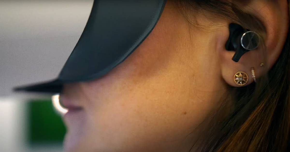 Seitenansicht einer Frau mit VR-Brille und einem In-Ear-Kopfhörer.