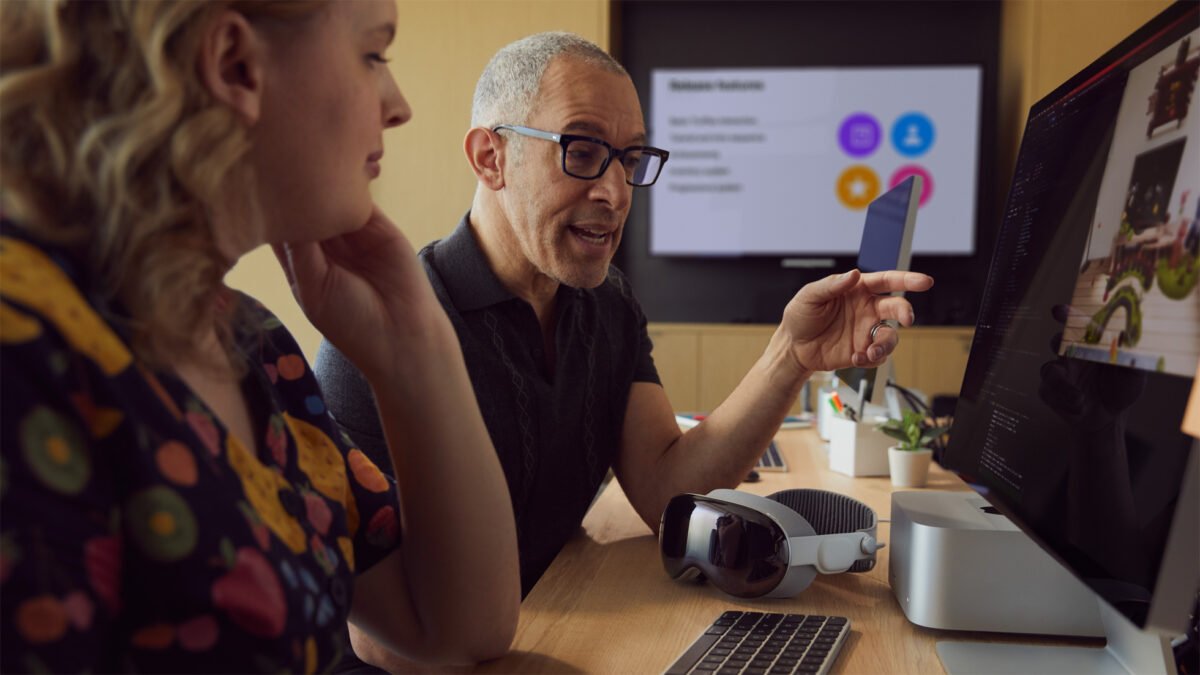 Zwei Entwickelnde vor dem SDK der Apple Vision Pro auf mehreren Monitoren.