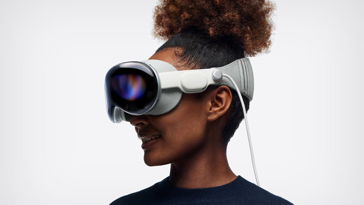 Frau mit hochgebundenem Haar trägt Apple Vision Pro vor weißem Hintergrund.