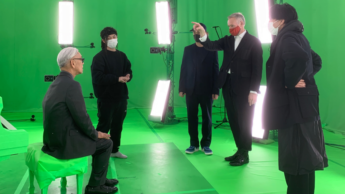 Pianist Ryuichi Sakamoto erhält in einem Green Room Anweisungen von einem Regisseur.