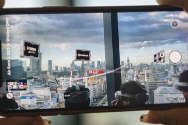 Blick auf Shibuya durchs Smartphone mit AR-Flugrennen im Bild