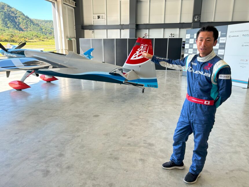 Pilot Yoshi Muroya zeigt auf seine Maschine im Hangar im Fukushima Air Park