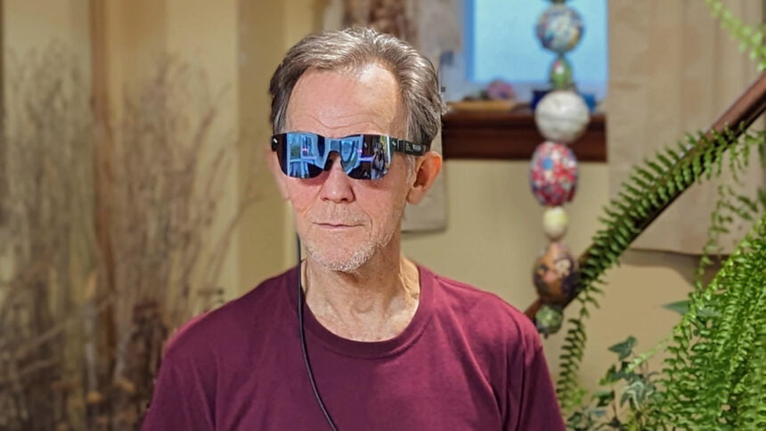 Alan Truly trägt die intelligente Brille RayNeo Air 2, die mit einem Samsung-Handy verbunden ist. 
