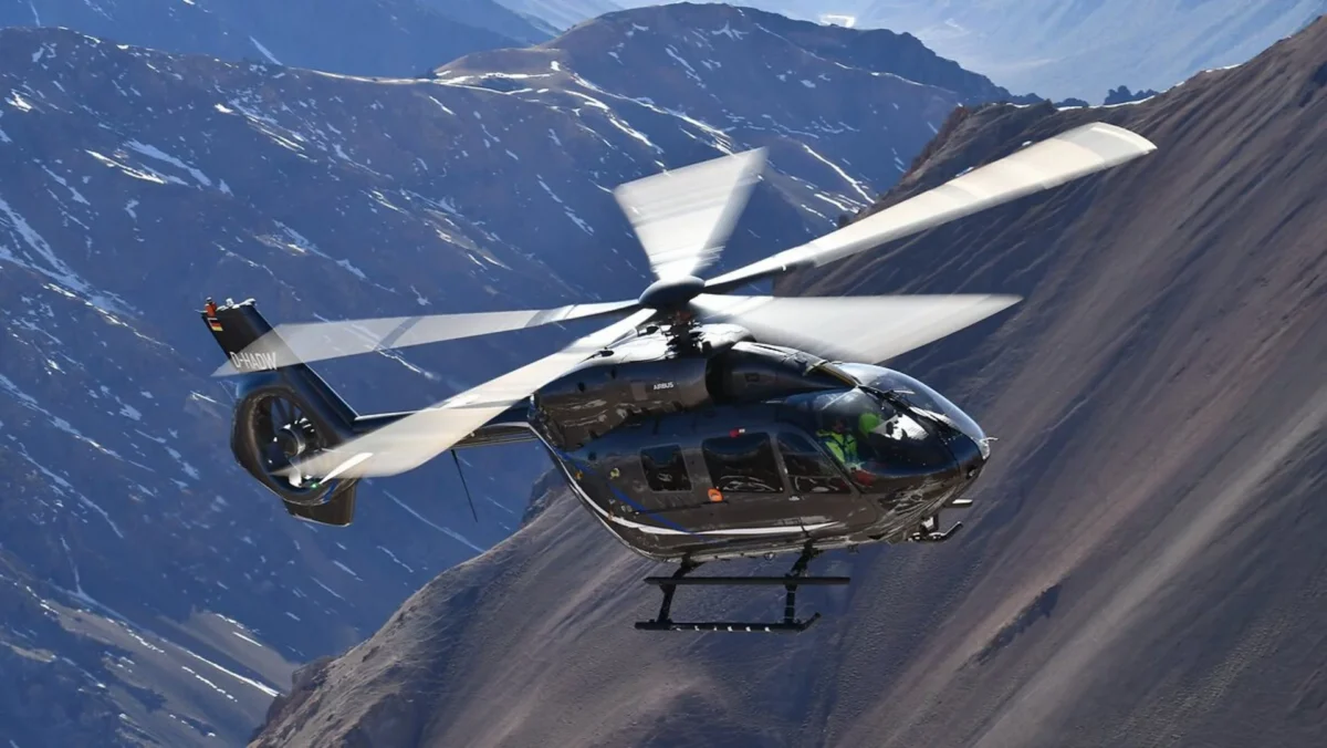Ein Helikopter im Flug, im Hintergrund sind Berge zu sehen