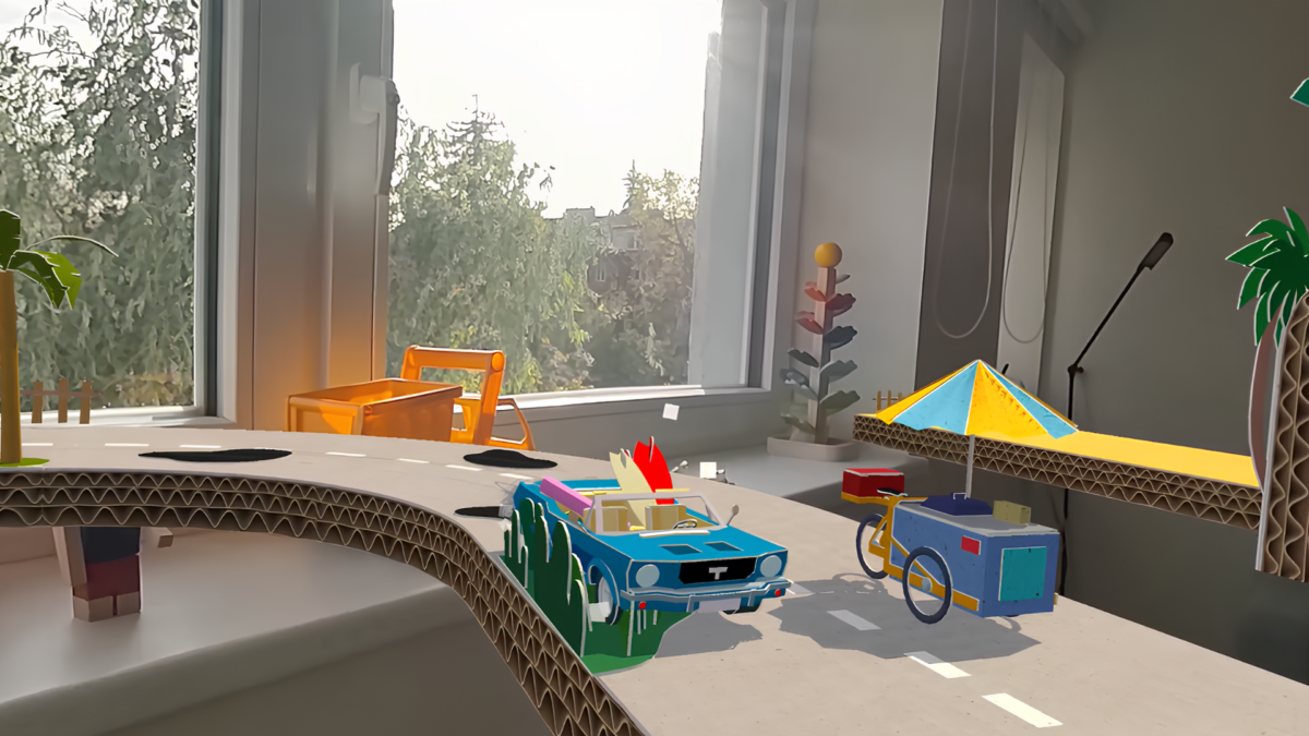 EIne virtuelle Spielzeugautobahn ist vor einem realen Fenster platziert. Darauf fährt ein kleines Auto an einem Imbisswagen vorbei.