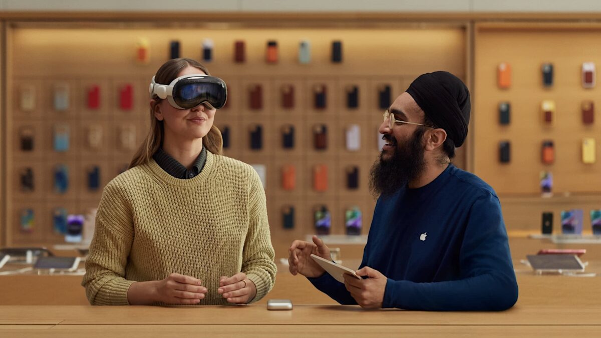 Frau probiert im App Store eine Vision Pro, neben ihr ein Store-Angestellter.