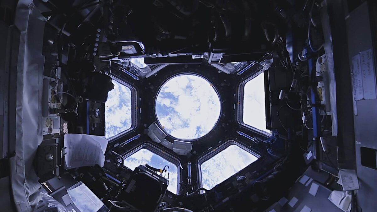 Blick in die Kuppel der ISS, dahinter Planet Erde.