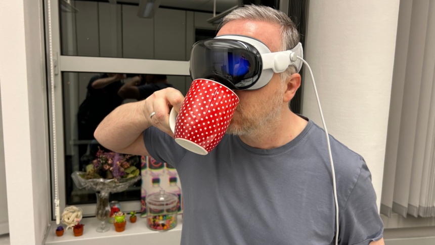 Mann mit Apple Vision Pro auf dem Kopf trinkt aus Kaffeetasse