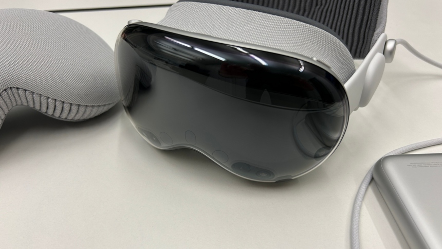 VR/AR-Brille Apple Vision Pro liegt auf einem Tisch zwischen der Schutzhülle und der Batterie