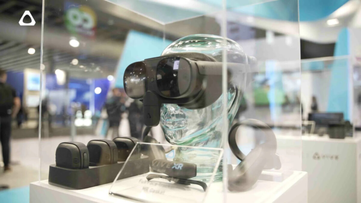 Eine Ladestation für VR-Körpertracker, eine VR-Brille und Controller in einer gläsernen Vitrine.