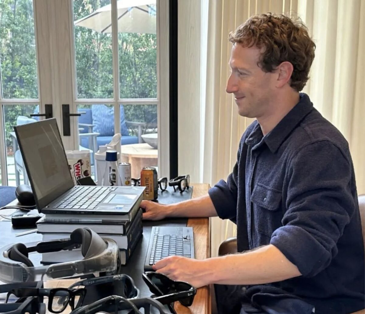 Mark Zuckerberg an seinem Schreibtisch, der mit VR- und AR-Brillen gepflastert ist.