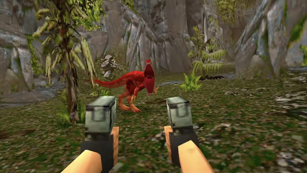 Lara Croft aus der Egoperspektive. Zwei Pistolen, die auf einen roten Raptor gerichtet sind. Grafik von 1996.