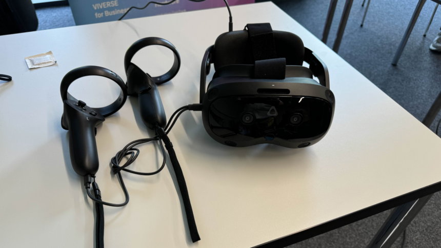 Die VR-Brille HTC Vive Focus Vision und zwei VR-Controller liegen auf einem weißen Tisch.