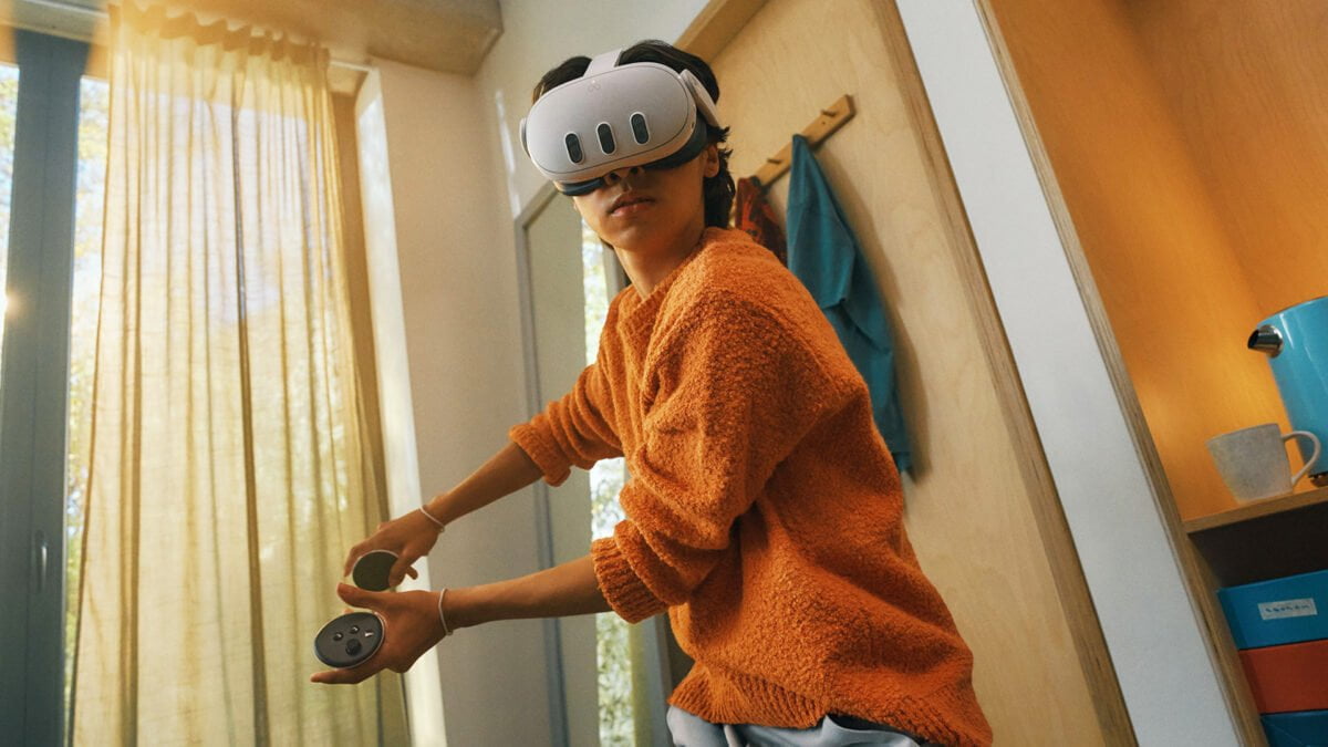 Ein Junge in orangefarbenem Pulli spielt in seinem Wohnzimmer mit der VR-Brille Meta Quest 3.